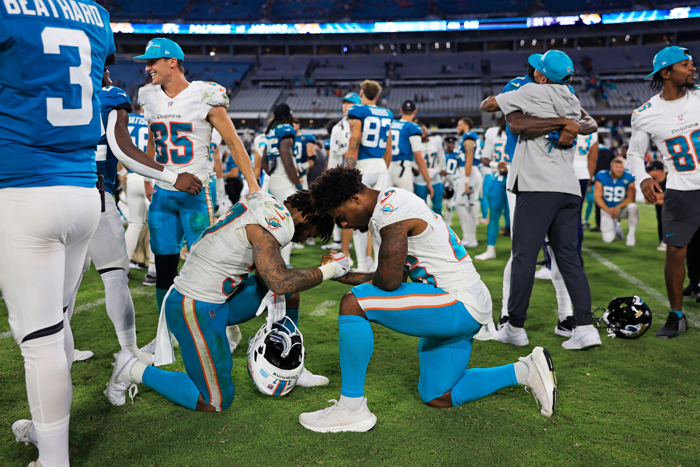 Former Huskies Myles Gaskin and Salvon Ahmed share in a prayer after a player went down in an August exhibition game.